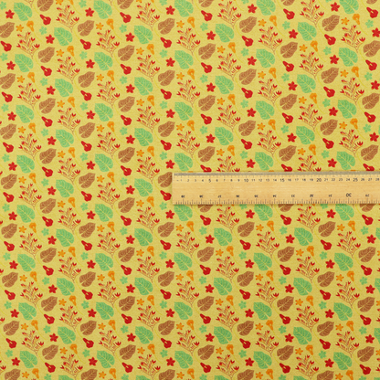 A yellow upholstery fabric featuring a vibrant tropical pattern of red, green, and brown leaves and flowers.