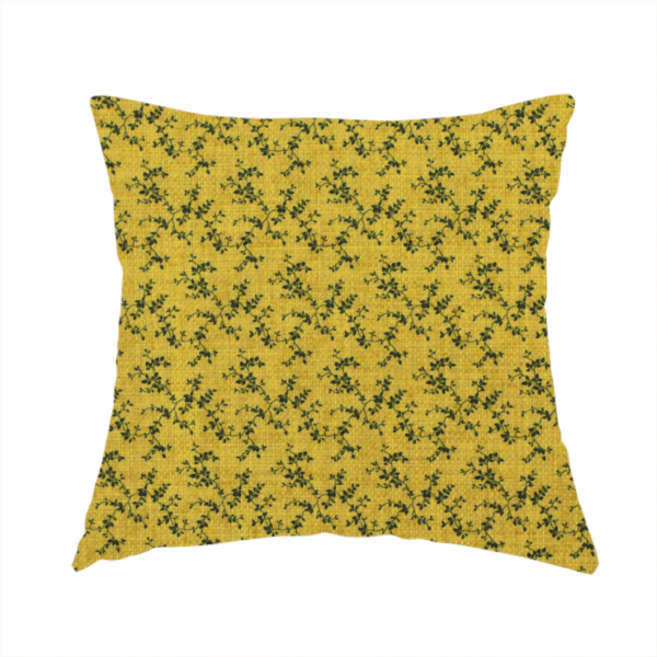 The fabric used to create this handmade cushion is a mustard yellow fabric featuring a dense, repeating pattern of small dark green or black trailing vines with tiny leaves and a subtle woven texture.