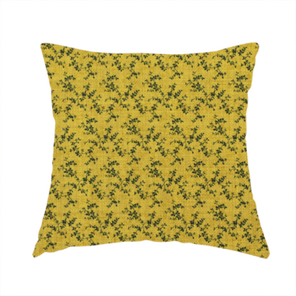 The fabric used to create this handmade cushion is a mustard yellow fabric featuring a dense, repeating pattern of small dark green or black trailing vines with tiny leaves and a subtle woven texture.