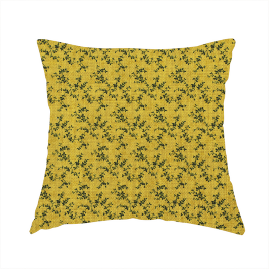 The fabric used to create this handmade cushion is a mustard yellow fabric featuring a dense, repeating pattern of small dark green or black trailing vines with tiny leaves and a subtle woven texture.