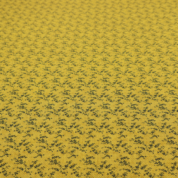 Mustard yellow fabric featuring a dense, repeating pattern of small dark green or black trailing vines with tiny leaves and a subtle woven texture.