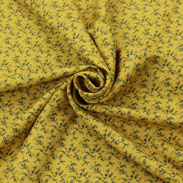 Mustard yellow fabric featuring a dense, repeating pattern of small dark green or black trailing vines with tiny leaves and a subtle woven texture.