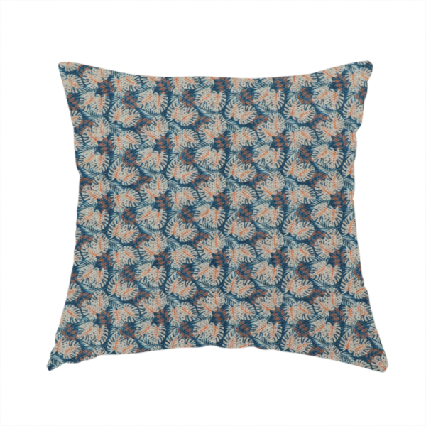 The fabric used to create this handmade cushion is a dark blue and slate textured fabric featuring a dense, repeating mosaic pattern of small tropical leaves in shades of cream and rust orange.