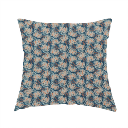 The fabric used to create this handmade cushion is a dark blue and slate textured fabric featuring a dense, repeating mosaic pattern of small tropical leaves in shades of cream and rust orange.