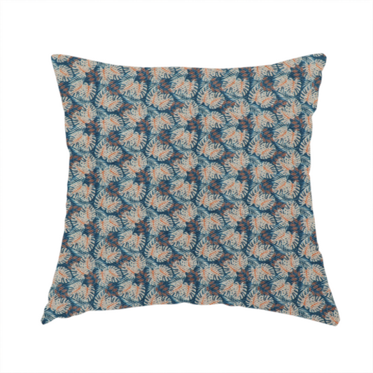 The fabric used to create this handmade cushion is a dark blue and slate textured fabric featuring a dense, repeating mosaic pattern of small tropical leaves in shades of cream and rust orange.