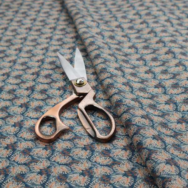 A dark blue and slate textured fabric featuring a dense, repeating mosaic pattern of small tropical leaves in shades of cream and rust orange.
