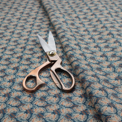 A dark blue and slate textured fabric featuring a dense, repeating mosaic pattern of small tropical leaves in shades of cream and rust orange.