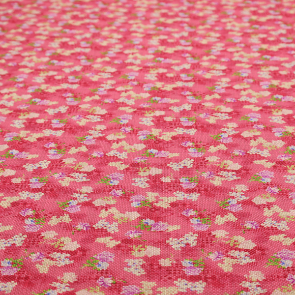 A vibrant raspberry pink fabric featuring a dense, repeating pattern of small white, purple, and green floral clusters over a subtle checked texture.