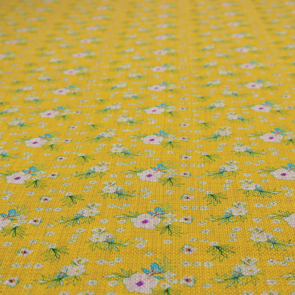 Textured mustard yellow fabric featuring a repeating micro floral pattern of small white and pink blossoms with green leaves and blue accents.