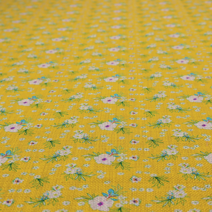 Textured mustard yellow fabric featuring a repeating micro floral pattern of small white and pink blossoms with green leaves and blue accents.