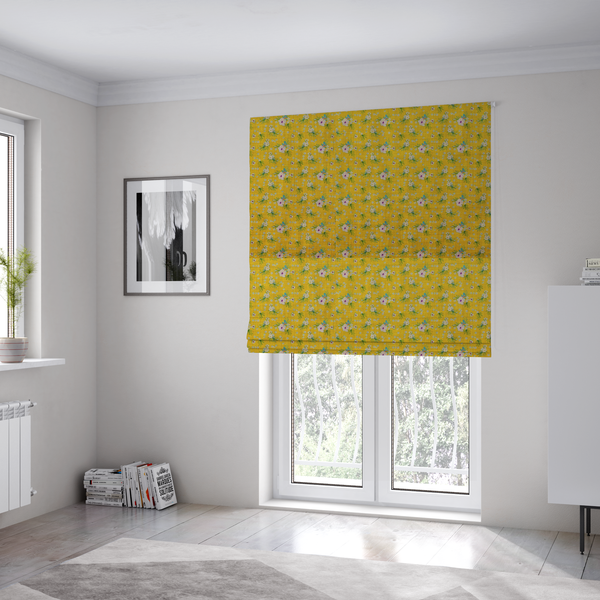 The fabric used to create these Roman blinds is a textured mustard yellow fabric featuring a repeating micro floral pattern of small white and pink blossoms with green leaves and blue accents.