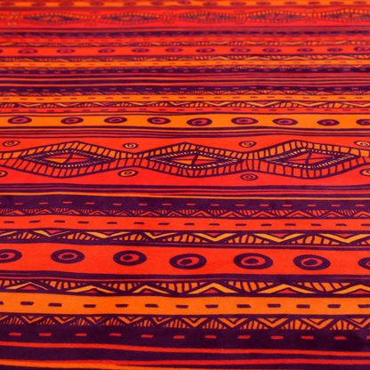 A vibrant orange and red fabric featuring a repeating tribal geometric and striped pattern.