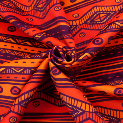 A vibrant orange and red fabric featuring a repeating tribal geometric and striped pattern.