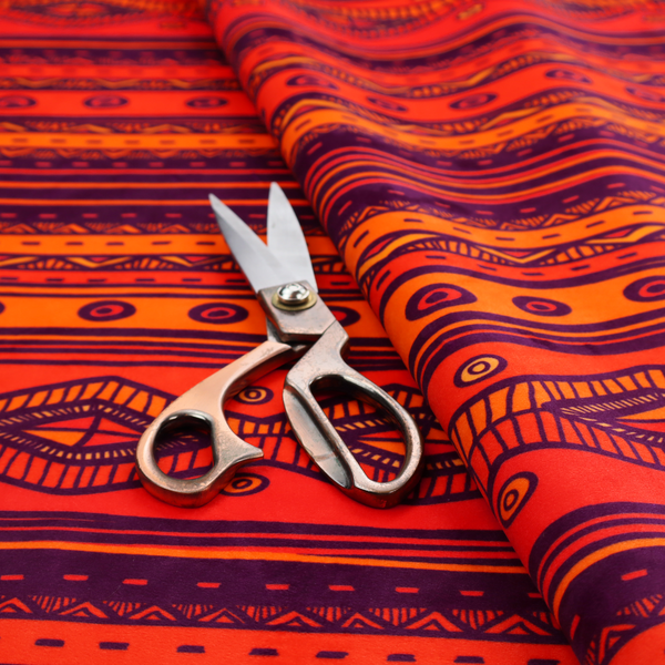 A vibrant orange and red fabric featuring a repeating tribal geometric and striped pattern.