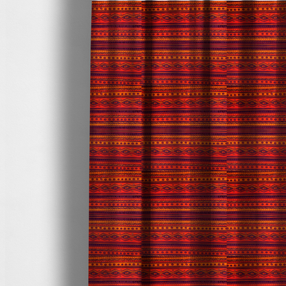 The fabric used to create these made-to-measure curtains is a vibrant orange and red fabric featuring a repeating tribal geometric and striped pattern.