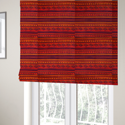 The fabric used to create these Roman blinds is a vibrant orange and red fabric featuring a repeating tribal geometric and striped pattern.