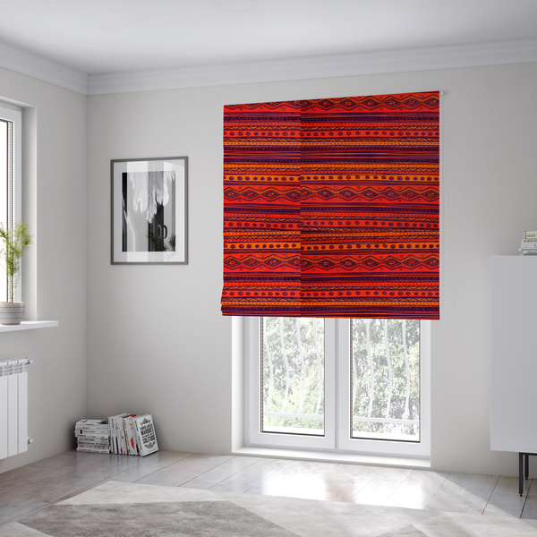 The fabric used to create these Roman blinds is a vibrant orange and red fabric featuring a repeating tribal geometric and striped pattern.
