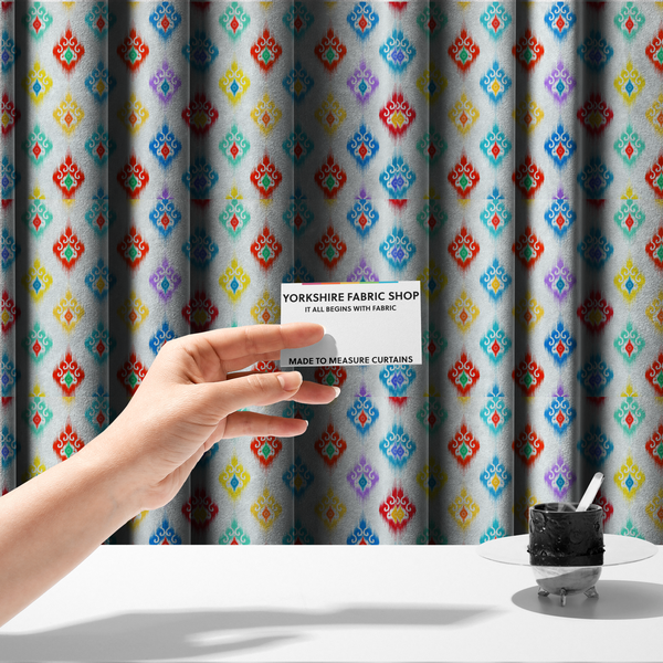 The fabric used to create these made-to-measure curtains is a colourful, patterned textile with an ikat-style design and repeating diamond motifs.
