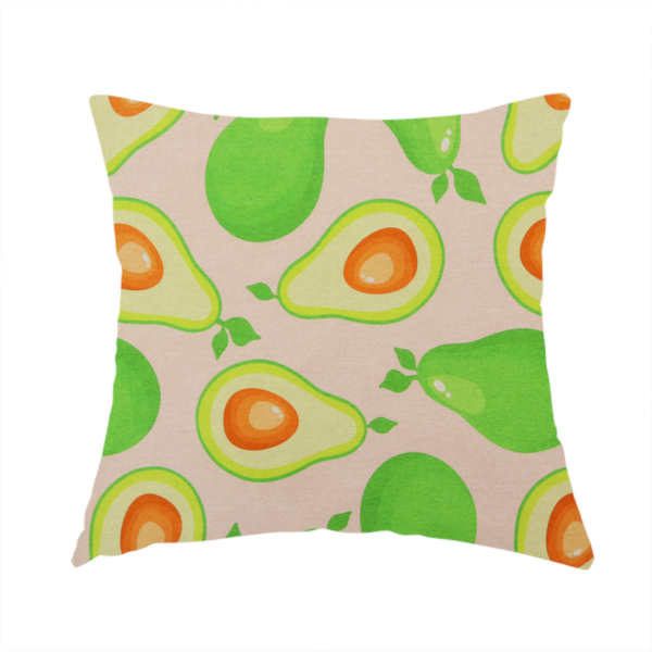 The fabric used to create this handmade cushion is a repeating pattern fabric featuring whimsical illustrations of whole green avocados with small leaves and sliced avocado halves showing bright orange pits, all scattered across a light pink background.