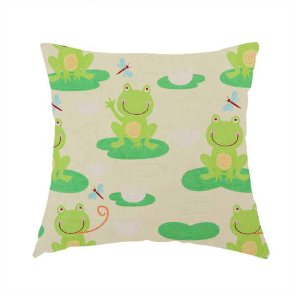 The fabric used to create this handmade cushion is a repeating pattern fabric featuring cute cartoon green frogs sitting on bright green lily pads, interspersed with blue and red dragonflies and white water lilies on a light cream background.