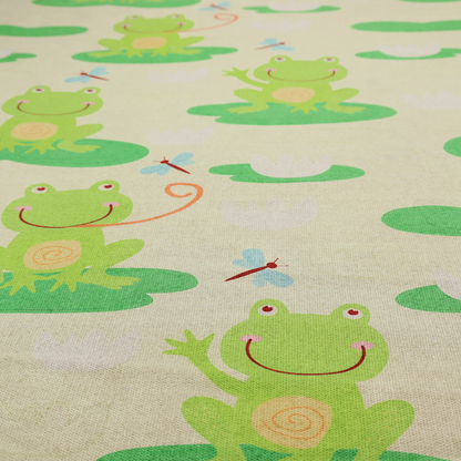 A repeating pattern fabric featuring cute cartoon green frogs sitting on bright green lily pads, interspersed with blue and red dragonflies and white water lilies on a light cream background.