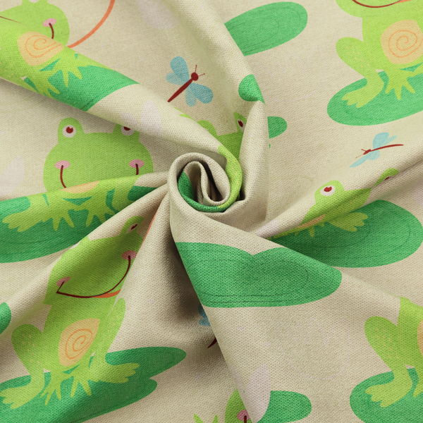A repeating pattern fabric featuring cute cartoon green frogs sitting on bright green lily pads, interspersed with blue and red dragonflies and white water lilies on a light cream background.
