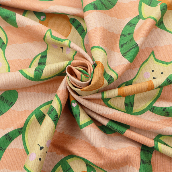 A playful repeating pattern fabric featuring whimsical illustrated "avocatos"—cats shaped like avocado halves with green striped tails and orange pits—over a light peach background with horizontal orange stripes.