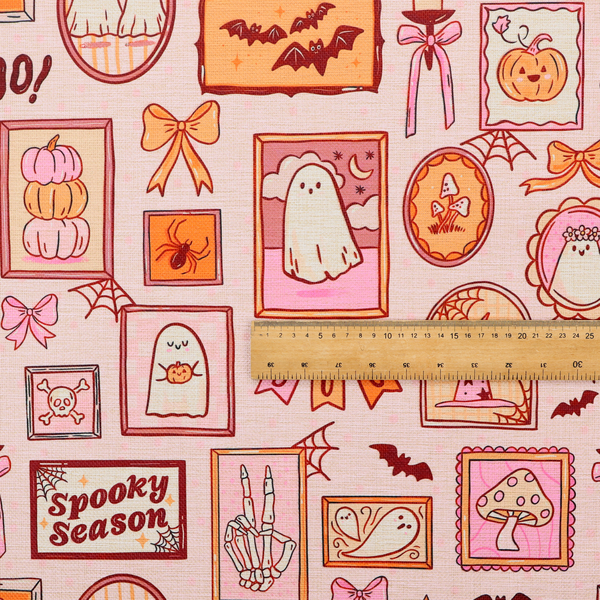 A seamless, repeating Halloween-themed pattern featuring a pink gallery wall filled with framed art, including cute ghosts, stacked pumpkins, a witch hat, a "Spooky Season" sign, bats, mushrooms, bows, spiderwebs, candles, and a skeletal peace sign hand on a light pink textured background.