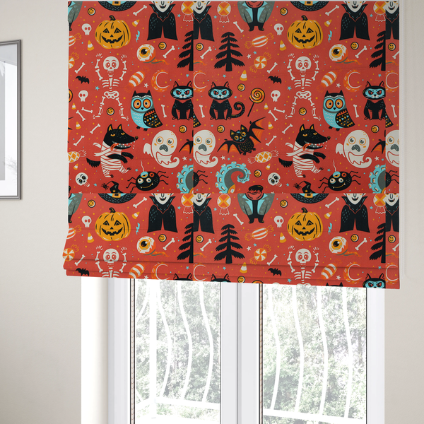 The fabric used to create these Roman blinds is a seamless, repeating Halloween-themed pattern featuring a vibrant red-orange background filled with a dancing skeleton, vampires, a mummified dog, a blue owl, black cats, a flying bat, ghosts, a jack-o'-lantern, candy, skulls, trees, and whimsical monsters.
