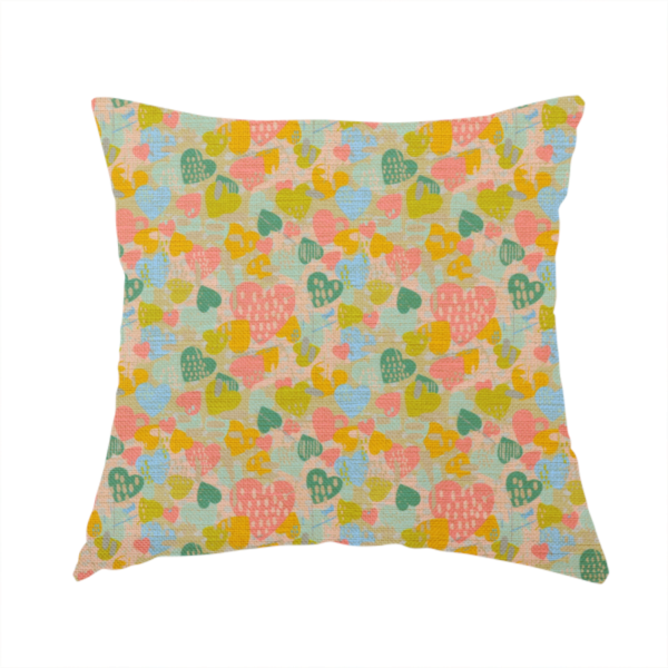 The fabric used to create this handmade cushion is a colourful repeating pattern of overlapping hearts in shades of pink, teal, yellow, and blue, set against a textured background.