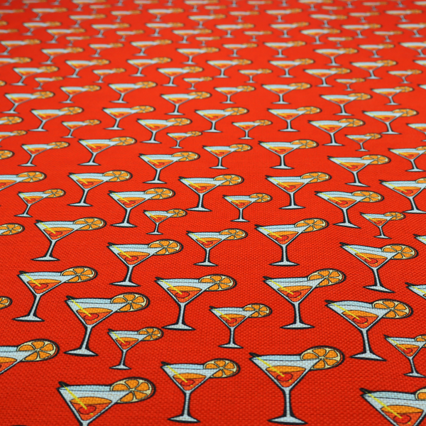 A repeating pattern of cocktail glasses filled with orange liquid, garnished with a slice of orange and a cherry, set against a bright red background.