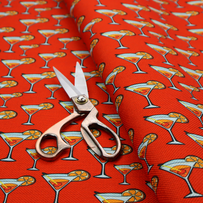 A repeating pattern of cocktail glasses filled with orange liquid, garnished with a slice of orange and a cherry, set against a bright red background.