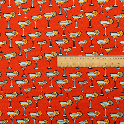 A repeating pattern of cocktail glasses filled with orange liquid, garnished with a slice of orange and a cherry, set against a bright red background.