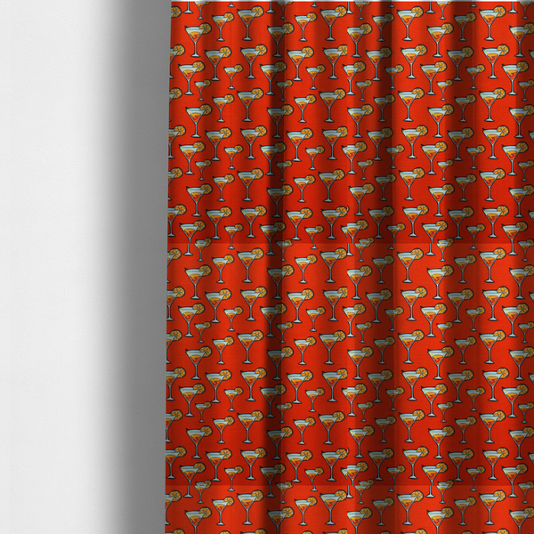 The fabric used to create these made-to-measure curtains is a repeating pattern of cocktail glasses filled with orange liquid, garnished with a slice of orange and a cherry, set against a bright red background.