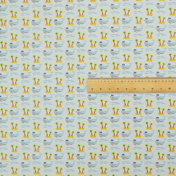 A repeating pattern of small blue whales wearing captain's hats swimming near tiny tropical islands with palm trees, set against a light grey background with small blue wave lines.
