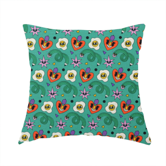 The fabric used to create this handmade cushion is a repeating pattern of quirky, cartoonish motifs including smiling eggs, stylized red hearts with faces, wiggly green pencils, and pink star-like shapes on a teal background.