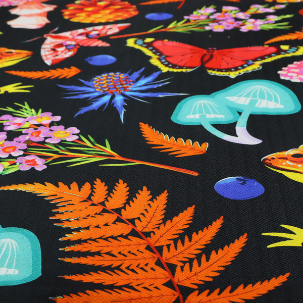 A vibrant, repeating botanical pattern on a black background featuring bright red butterflies, orange spotted frogs, orange pinecones, pink and white mushrooms, orange fern fronds, blue berries, and purple wildflowers.