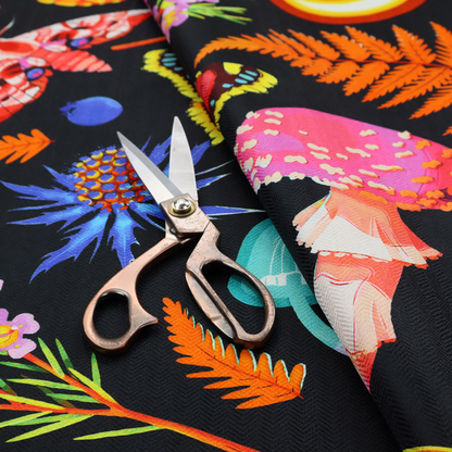 A vibrant, repeating botanical pattern on a black background featuring bright red butterflies, orange spotted frogs, orange pinecones, pink and white mushrooms, orange fern fronds, blue berries, and purple wildflowers.