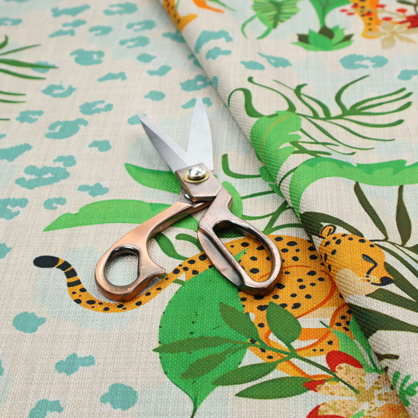 A repeating pattern featuring spotted cheetahs amidst lush green tropical leaves, red floral accents, and a teal leopard print background.