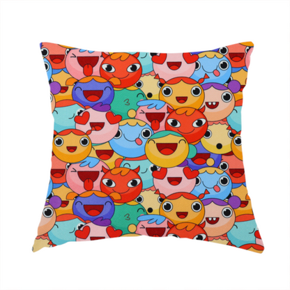 The fabric used to create this handmade cushion is a dense, overlapping pattern of colourful, stylized cartoon faces featuring wide smiles, sticking-out tongues, and various cheerful or cheeky expressions in vibrant shades of pink, orange, yellow, blue, and purple.