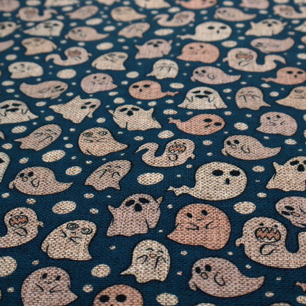 A dark blue fabric patterned with an all-over, repeating design of light beige and peach cartoon ghosts with various cute and silly facial expressions, interspersed with small white polka dots.