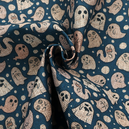 A dark blue fabric patterned with an all-over, repeating design of light beige and peach cartoon ghosts with various cute and silly facial expressions, interspersed with small white polka dots.