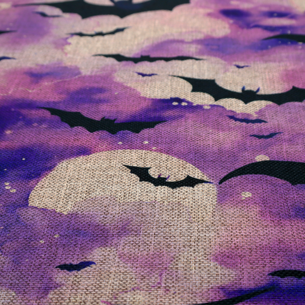 A watercolour-style Halloween fabric featuring a spooky night sky in shades of purple and pink, filled with silhouettes of flying black bats and two pale full moons.