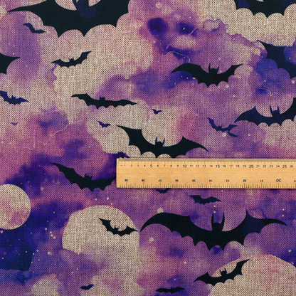 A watercolour-style Halloween fabric featuring a spooky night sky in shades of purple and pink, filled with silhouettes of flying black bats and two pale full moons.
