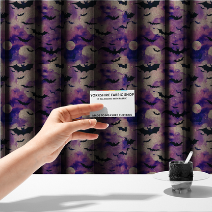 The fabric used to create these made-to-measure curtains is a watercolour-style Halloween fabric featuring a spooky night sky in shades of purple and pink, filled with silhouettes of flying black bats and two pale full moons.