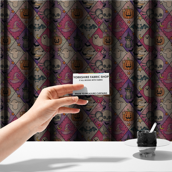 The fabric used to create these made-to-measure curtains is a Halloween-themed harlequin pattern fabric with diamond-shaped sections in purple, pink, and beige, featuring cartoon illustrations of Jack-o'-lanterns, a witch's cat, ghosts, bats, skulls, spiders, stars, and crescent moons.