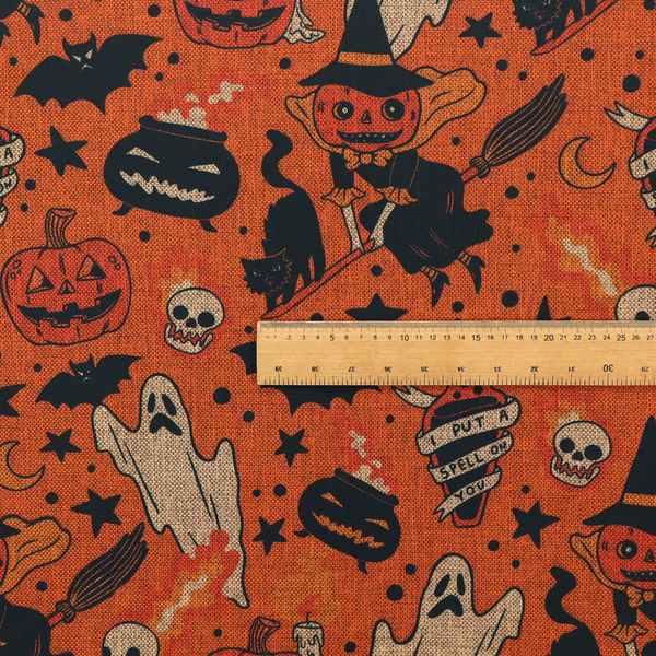 An orange Halloween fabric patterned with various black illustrations, including a witch with a pumpkin head flying on a broomstick, a black cat, ghosts, skulls, potion bottles with the text "I put a spell on you," bats, cauldrons, and stars.