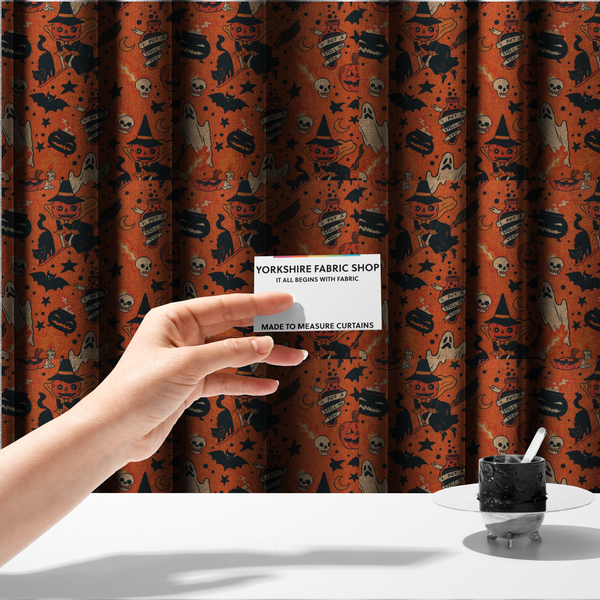 The fabric used to create these made-to-measure curtains is an orange Halloween fabric patterned with various black illustrations, including a witch with a pumpkin head flying on a broomstick, a black cat, ghosts, skulls, potion bottles with the text "I put a spell on you," bats, cauldrons, and stars.