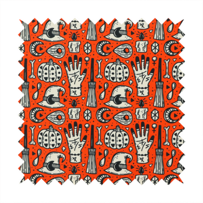 An orange Halloween fabric patterned with repeating black and white illustrations of patterned pumpkins, mystical hands with symbols, witch hats with crescent moons, brooms, candles, bones, and planchettes.