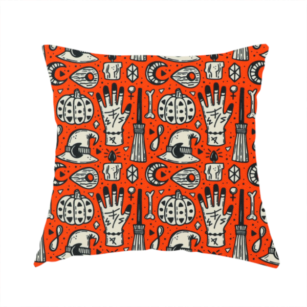 The fabric used to create this handmade cushion is an orange Halloween fabric patterned with repeating black and white illustrations of patterned pumpkins, mystical hands with symbols, witch hats with crescent moons, brooms, candles, bones, and planchettes.